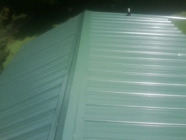 New green metal panels meeting at the ridge of a roof — Flat Roof Repair work by our crew in Jarrell