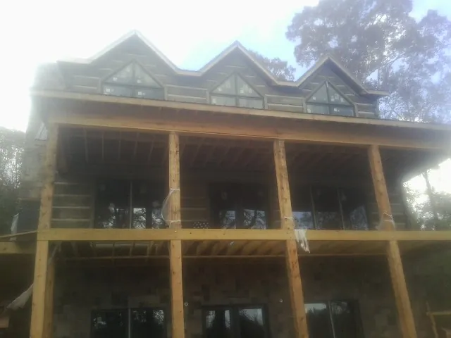 Dormers and porch framing on a large log home under construction — Roof Coating work by our crew in Jarrell