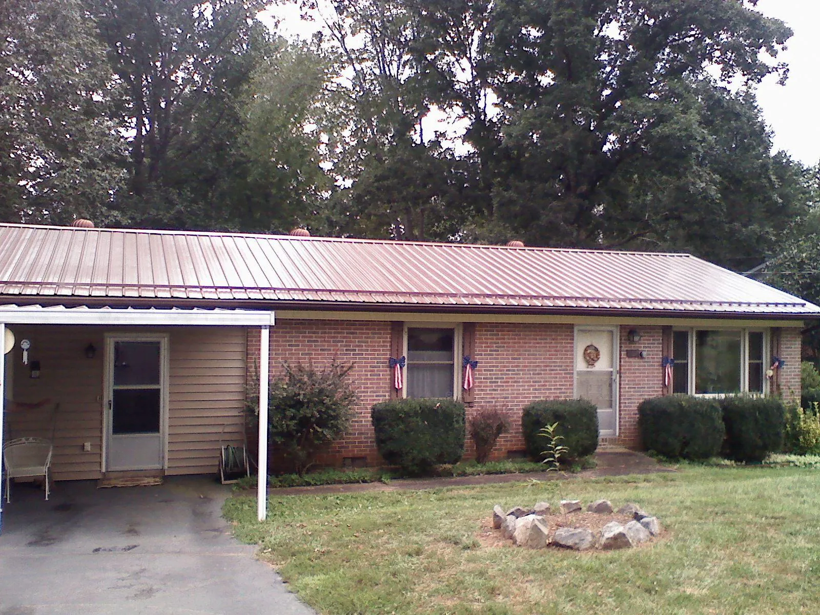 Bronze metal roof and carport on a brick ranch home — Roof Repair work by our crew in Jarrell