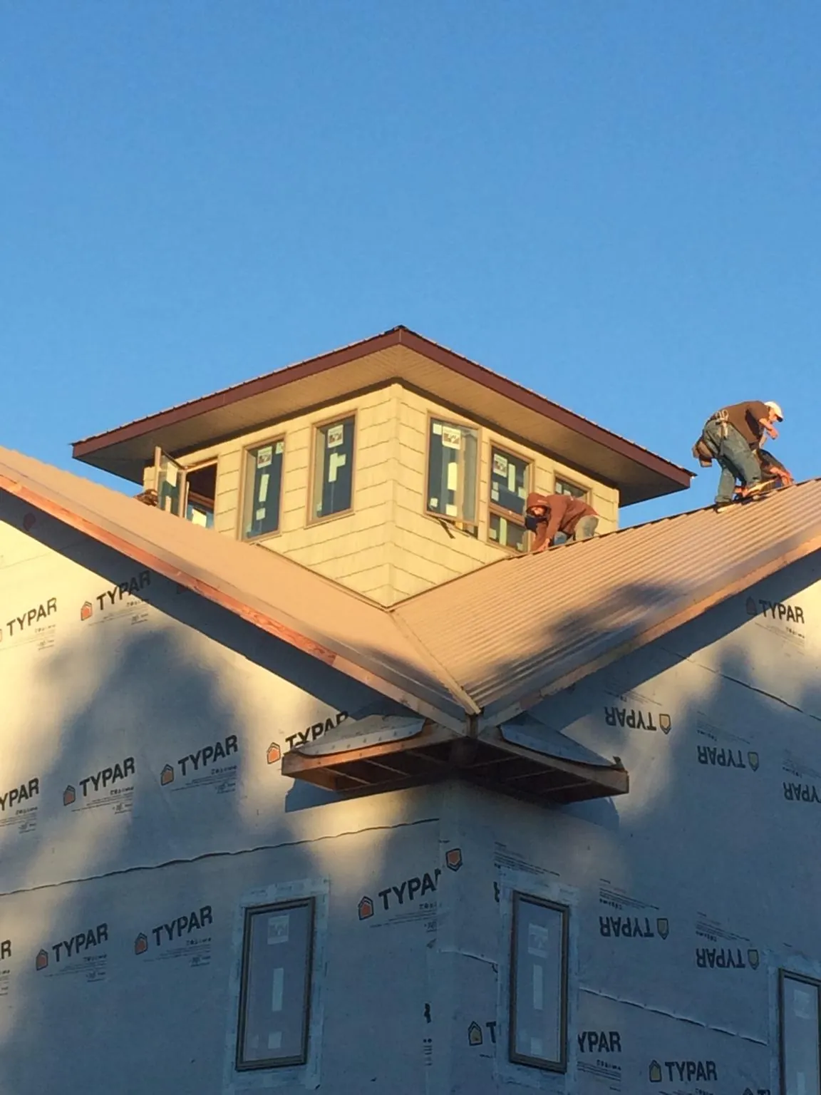 Roofers working around a rooftop cupola on a new metal roof at sunset — Roof Waterproofing in Jarrell by Roofing Brothers